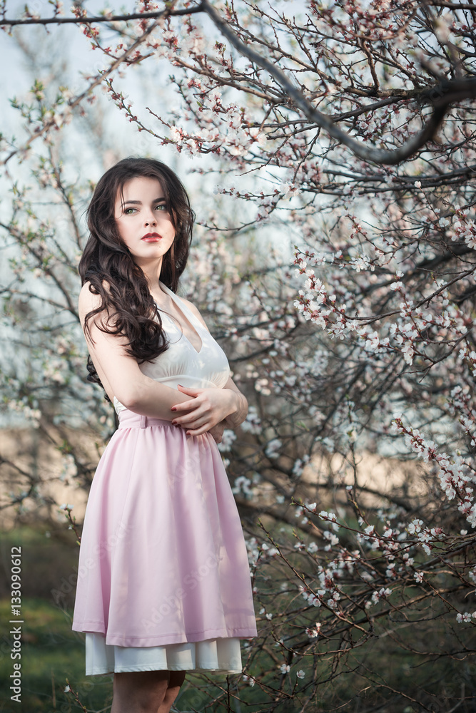 Beautiful girl standing at blossoming tree in the garden Beautiful girl standing at blossoming tree in the garden