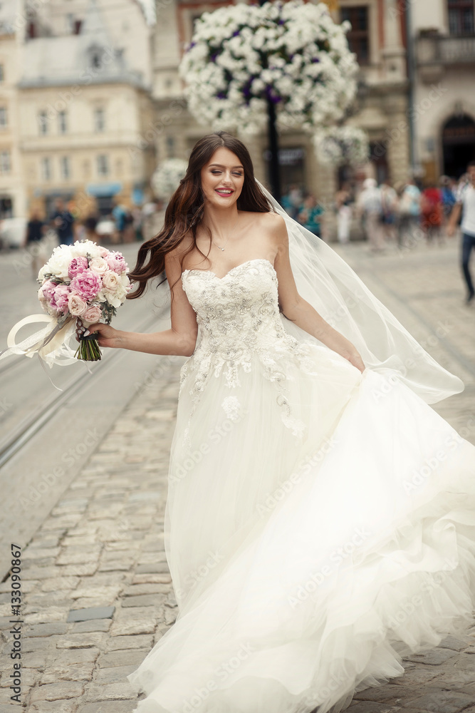 Stunning brunette bride with long hair whirls on an old street Stunning brunette bride with long hair whirls on an old street