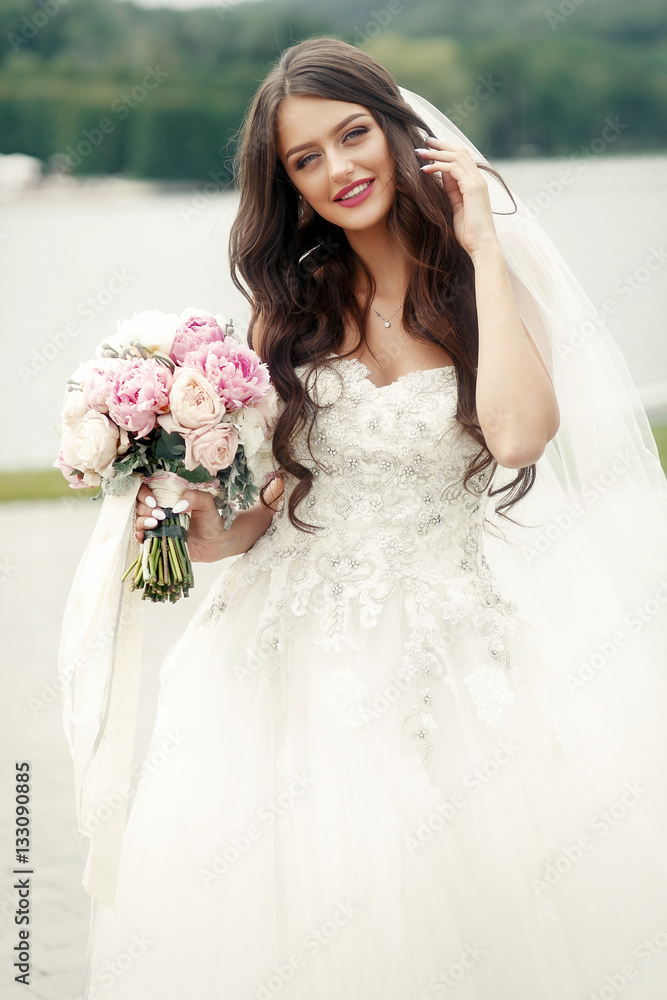 Adorable brunette bride holds pink wedding bouquet in her hand Adorable brunette bride holds pink wedding bouquet in her hand