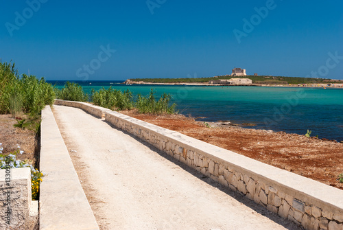 Road along the coastline in Portopalo (southern Sicily); the island of "Capo Passero" in the background