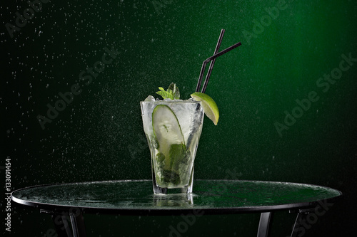 Fresh drink with ice, green mint and lime on black background