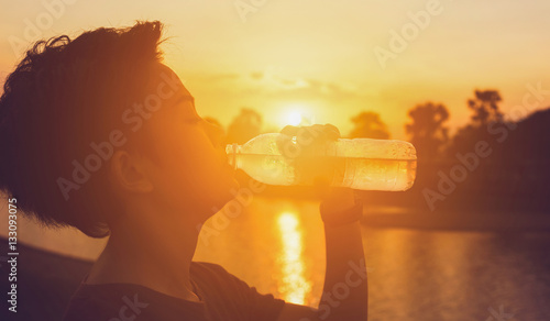 Female drinking a bottle of water on sunset