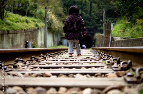 Little girl walking on the railway track
