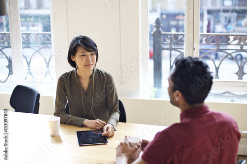 Asian businesswoman interviewing mixed race man in an office