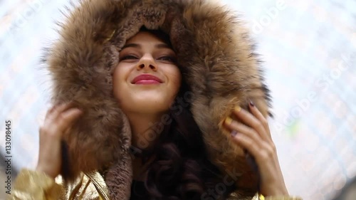 Portrait close up of young beautiful brunette woman in golden fur coat, indoor shop