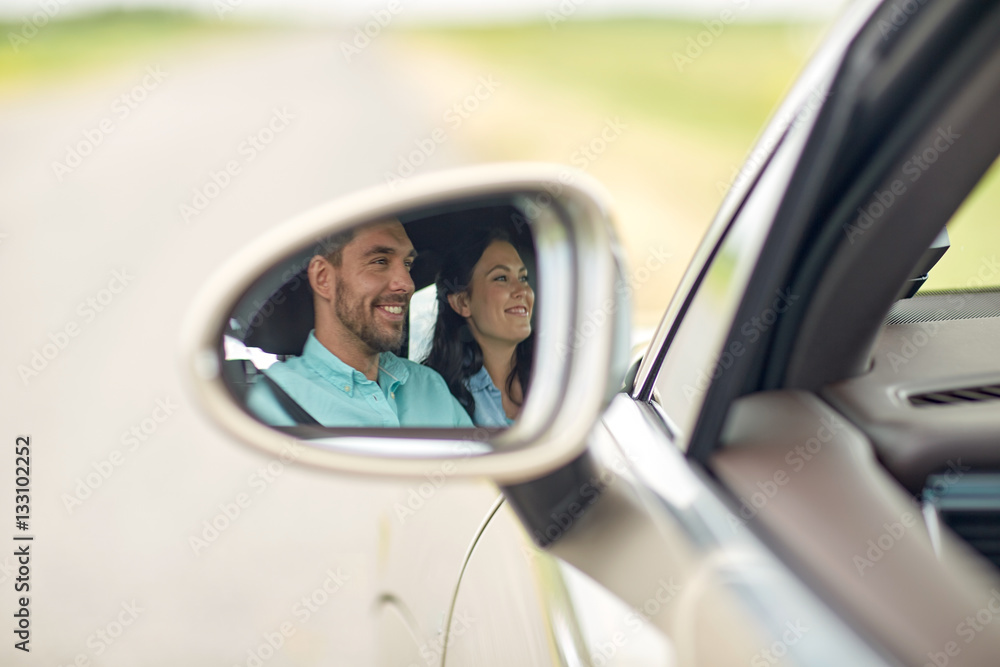 side mirror reflection of happy couple driving car