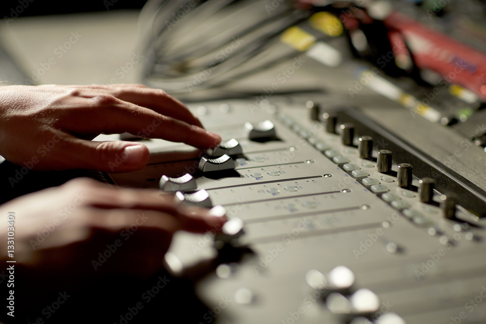 Fototapeta premium hands on mixing console in music recording studio