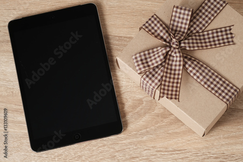 Blank tablet screen for text on wooden table with present