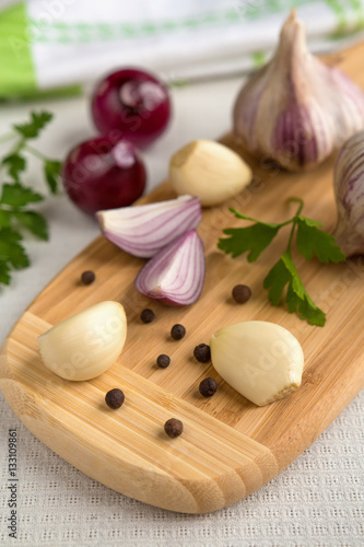 Fresh garlic, onion and spices on a light background closeup