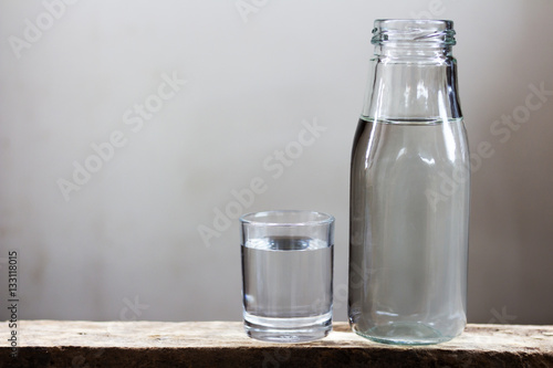 Fotografija Drinking water in glass and bottle on a wooden floor.
