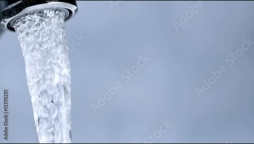 clean water running from faucet on blue background photo