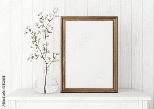 Vertical interior mock up with empty wooden frame and blooming twig on wooden wall background. 3D rendering.