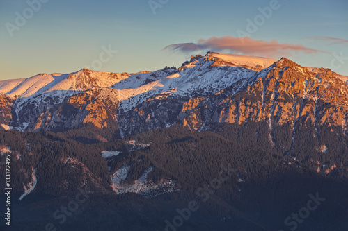 Great view of the snow capped Bucegi massif ridge in the warm colorful sunrise light, Carpathians mountains range, Romania. Spectacular hiking destinations. Romanian mountaineering attractions.