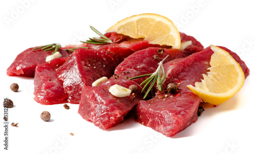Pieces of meat with garlic, lemon and rosemary on wooden board isolated. Raw beef.