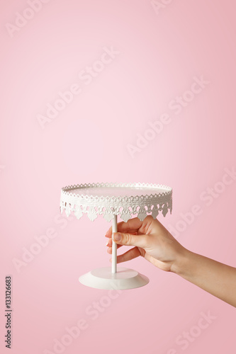 Woman hand holding a decorative plate on pastel background