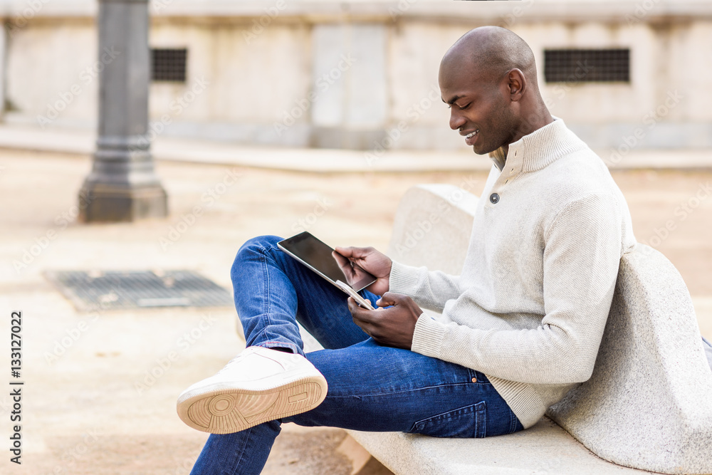Black young man looking at tablet computer and smartphone Black young man looking at tablet computer and smartphone