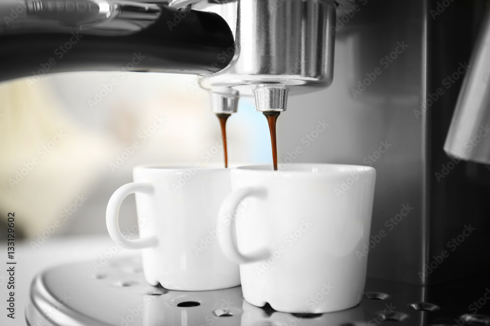 Fresh espresso pouring into cups from coffee machine Fresh espresso pouring into cups from coffee machine