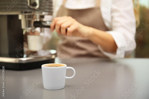 Cup of fresh espresso with female barista on background