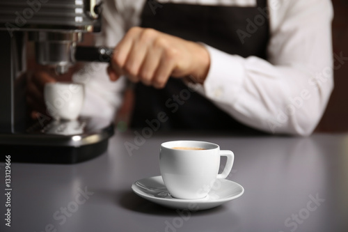 Cup of fresh espresso with male barista on background