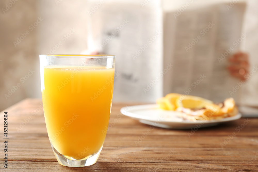 Fototapeta premium Glass of fresh orange juice and breakfast on table