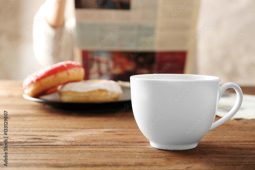 Cup of tea and tasty breakfast on table with person reading newspaper on background Cup of tea and tasty breakfast on table with person reading newspaper on background