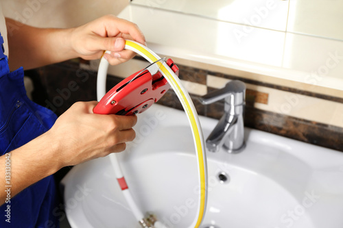 Plumber fixing water flexible hose in bathroom