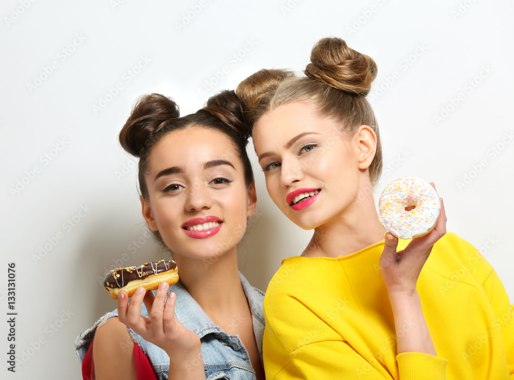 Funny young women with tasty donuts on white background Funny young women with tasty donuts on white background