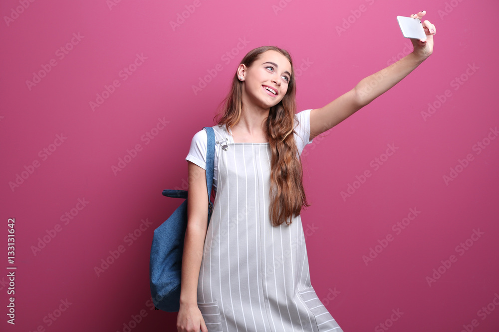 Pretty teenager girl taking selfie on color background Pretty teenager girl taking selfie on color background