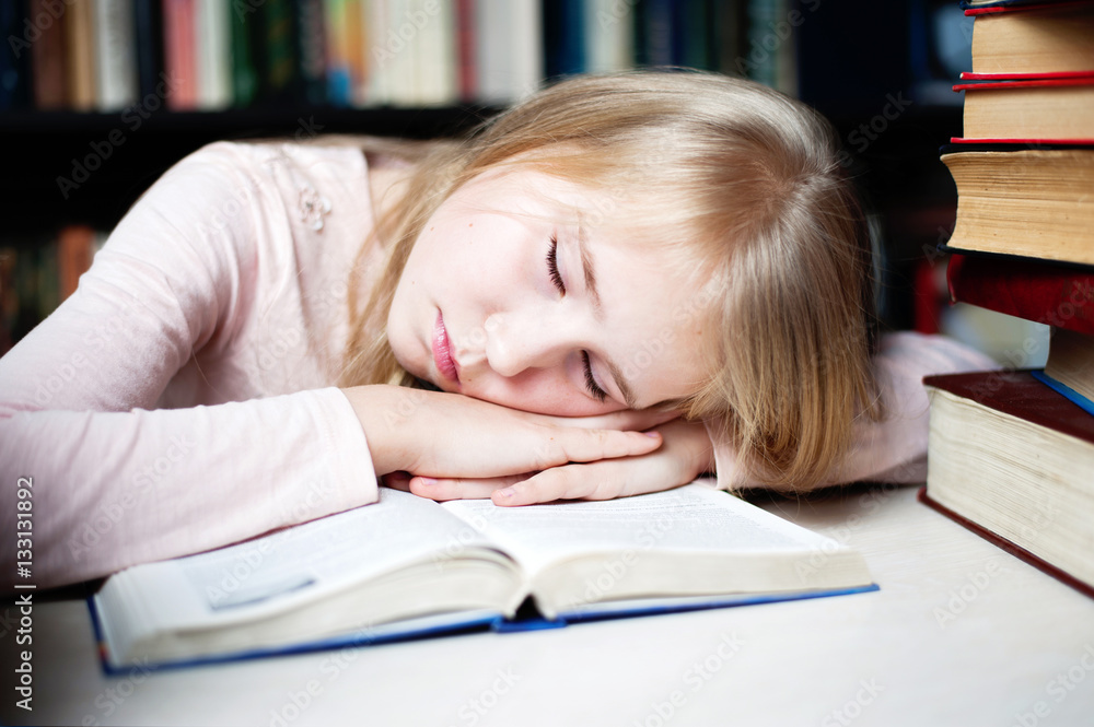 Cute little girl lying on table while doing her homework. Cute little girl lying on table while doing her homework.