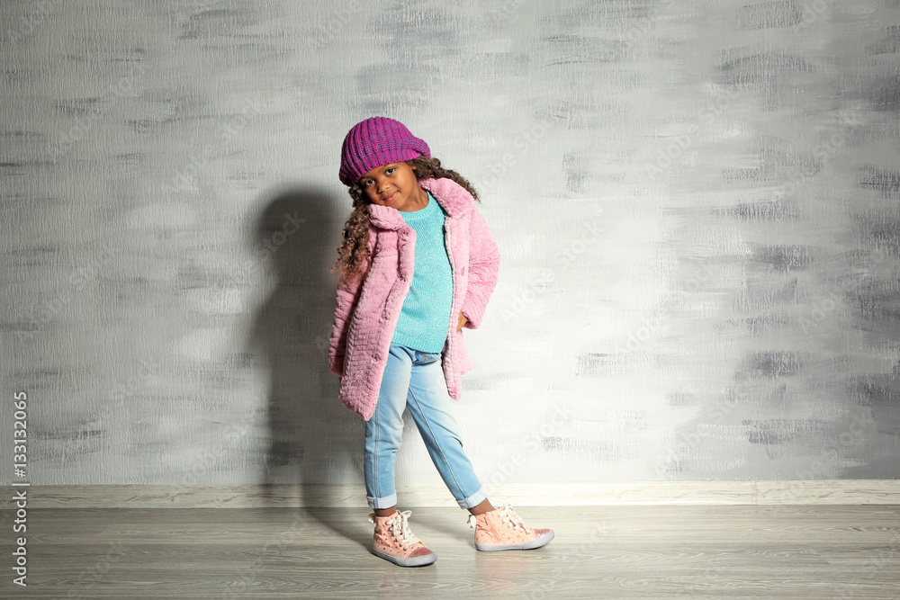 Cute little African American girl against grey wall. Fashion concept Cute little African American girl against grey wall. Fashion concept