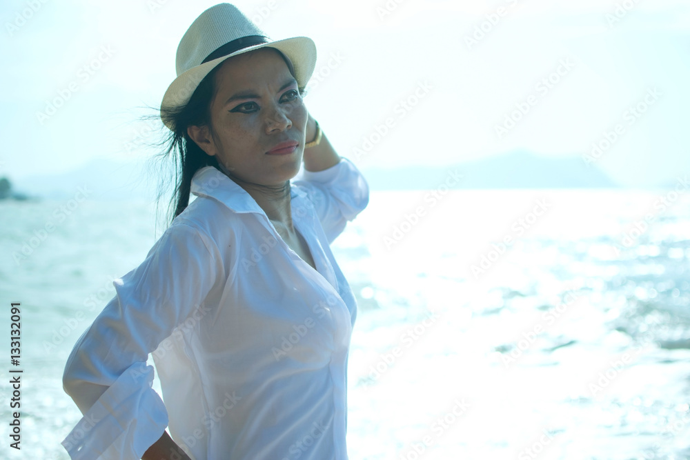 Sexy woman with white shirt and hat poses on the beach - glare effect Sexy woman with white shirt and hat poses on the beach - glare effect