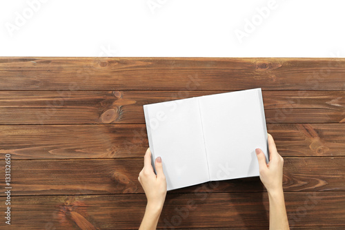 Female hands holding opened book on wooden background