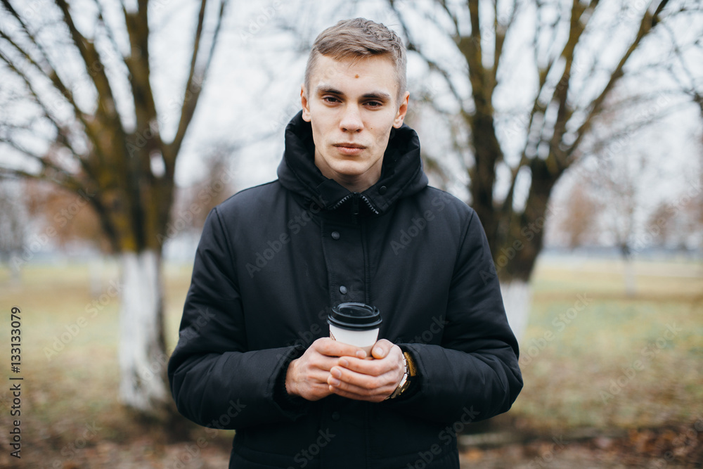 A man stands with a cup of coffee outdoors. Coffee to go A man stands with a cup of coffee outdoors. Coffee to go