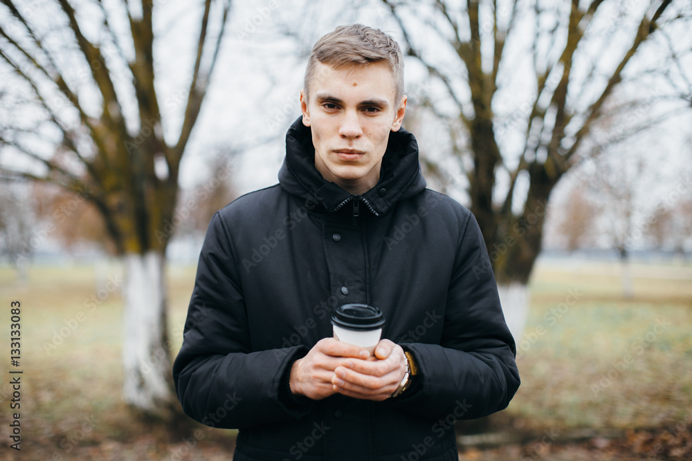 A man stands with a cup of coffee outdoors. Coffee to go A man stands with a cup of coffee outdoors. Coffee to go