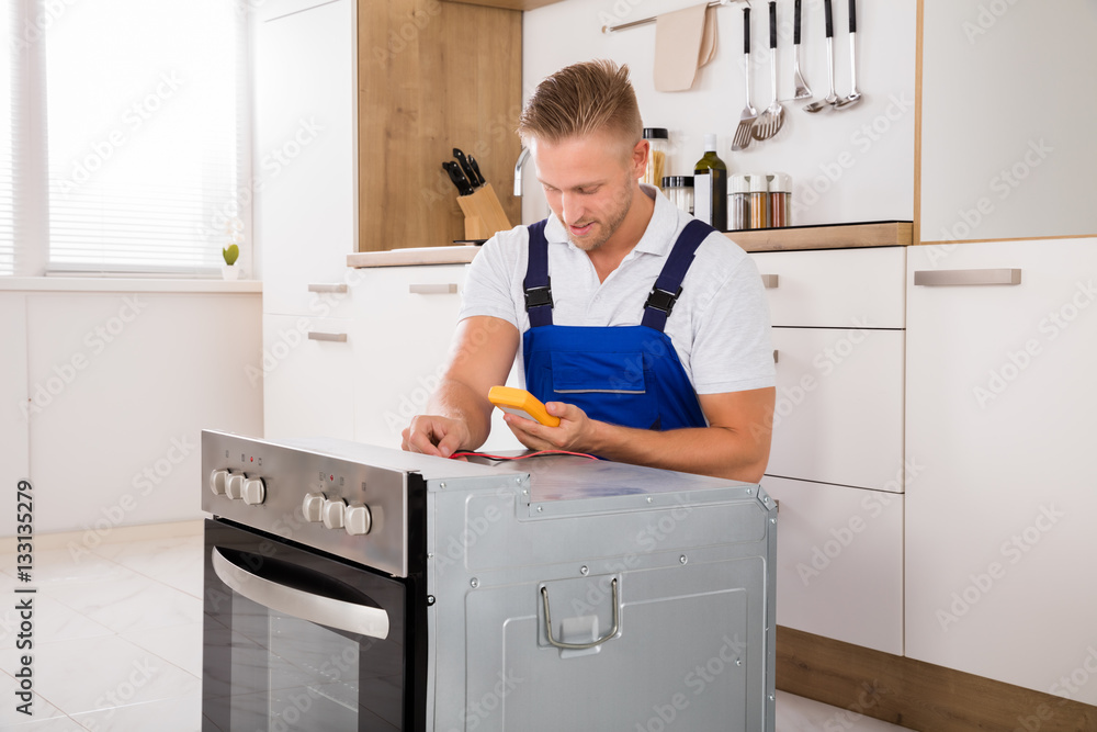 Technician Checking Oven With Digital Multimeter Technician Checking Oven With Digital Multimeter
