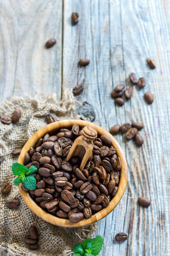 Roasted coffee beans and mint in a wooden bowl.