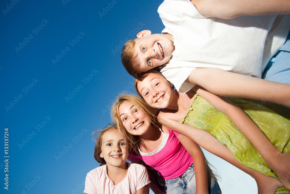 four happy beautiful children looking at camera from top in the sunny summer day and blue sky. looking at camera with funny face and toothy smile. view from below.
four happy beautiful children looking at camera from top in the sunny summer day and blue sky. looking at camera with funny face and toothy smile. view from below.