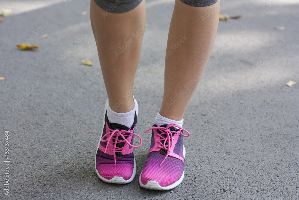 Young woman's legs with sneakers. Bright running shoes. Fitness woman in training shoes jogging outdoors in park. Young woman's legs with sneakers. Bright running shoes. Fitness woman in training shoes jogging outdoors in park.