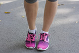 Young  woman's legs with sneakers. Bright  running  shoes. Fitness woman in training shoes jogging outdoors in park. 