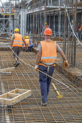 Canvas Print Construction workers carrying heavy steel bar