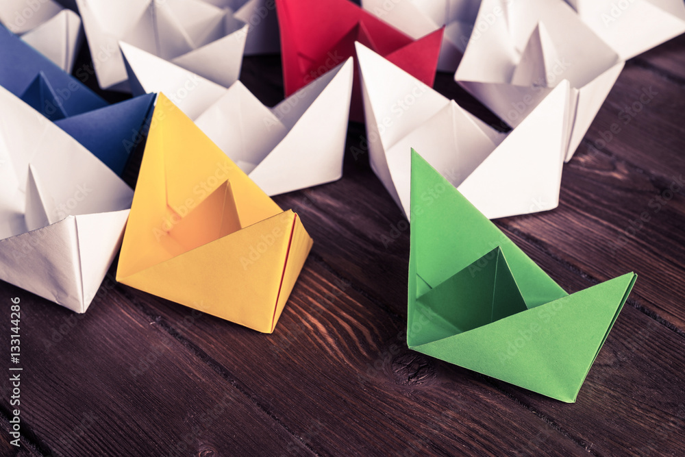 Business leadership concept with white and color paper boats on Business leadership concept with white and color paper boats on