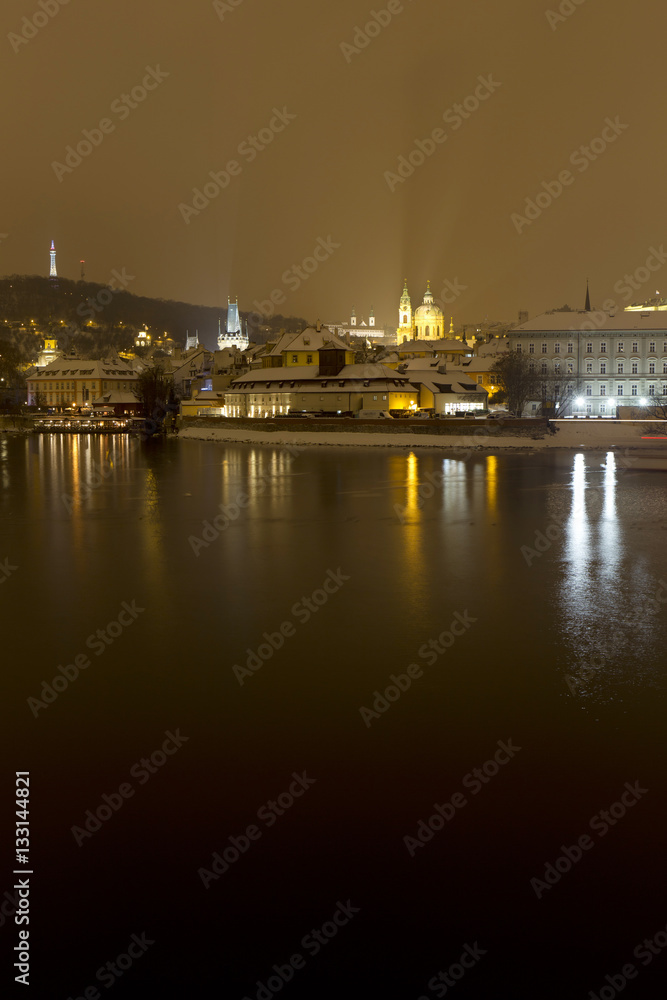 Night romantic snowy Prague St. Nicholas' Cathedral above River Vltava, Czech republic
