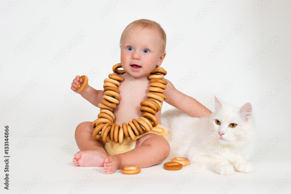 Funny baby sits with bunch of bagels and hugging a cat on white background. Funny baby sits with bunch of bagels and hugging a cat on white background.