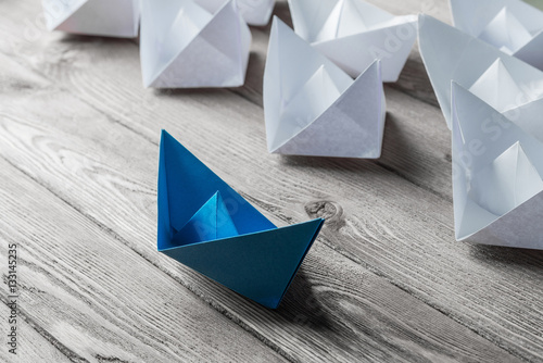 Business leadership concept with white and color paper boats on 