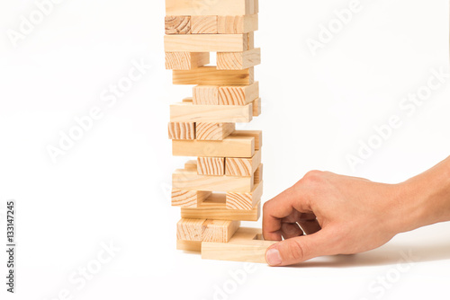 Tower of wooden blocks Jenga game and man's hand