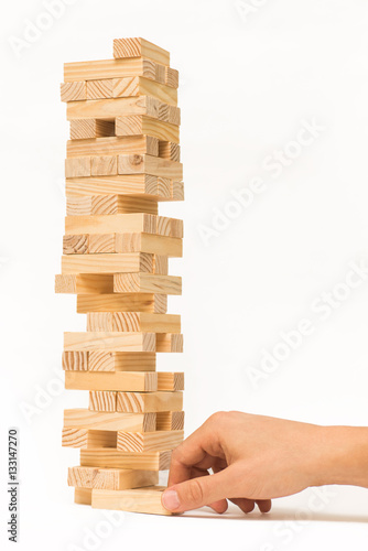 Tower of wooden blocks Jenga game and man's hand