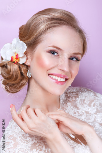 Beautiful bride with fashion wedding hairstyle - on pink background.Closeup portrait of young gorgeous bride. Wedding. Studio shot.