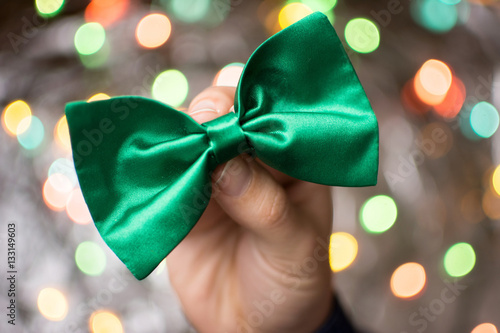 Male hand holding a green bow tie. photo