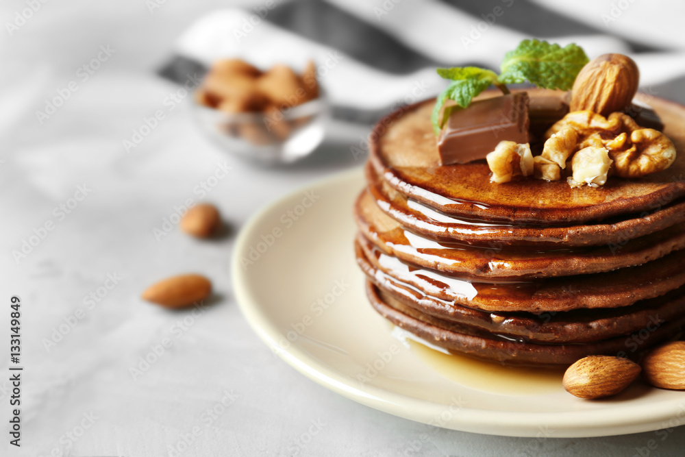 Delicious chocolate pancakes decorated with nuts and sweet syrup on plate Delicious chocolate pancakes decorated with nuts and sweet syrup on plate