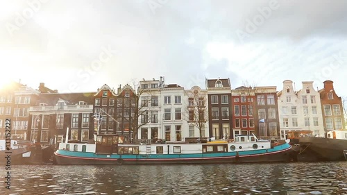Amsterdam, Netherlands - January 3: Slow motion video of view from the canal to the streets, canals with old flamish houses and bridges in Amsterdam, Netherlands. photo